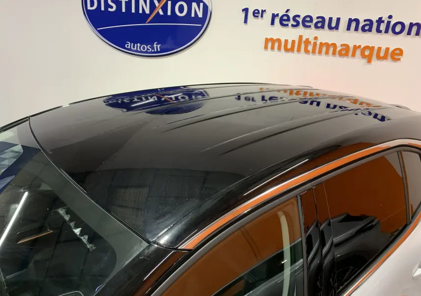 Toit panoramique noir brillant du Citroën C5 Aircross hybride blanc vu de dessus côté droit, reflet d'enseigne en arrière-plan.