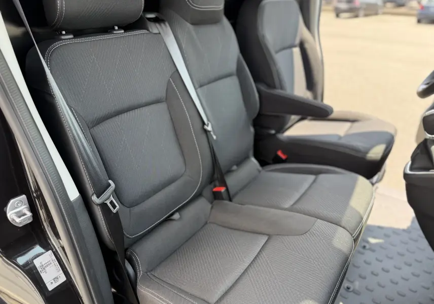 Vue rapprochée des sièges avant en tissu noir avec accoudoir dans un Renault Trafic Fourgon noir crépuscule 2025.
