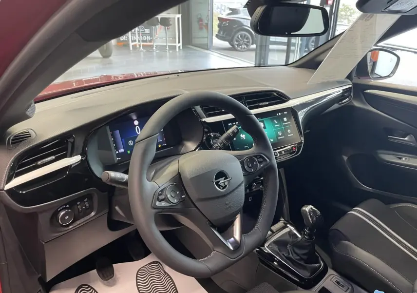 Vue intérieure côté conducteur de l’Opel Corsa rouge 2026, volant cuir, tableau de bord numérique et écran tactile 10 pouces.