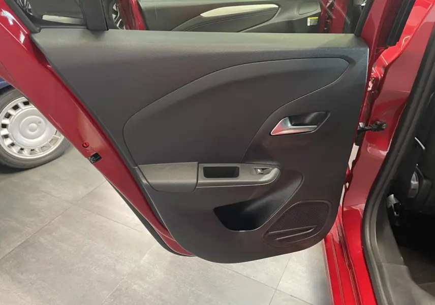 Vue rapprochée de la porte arrière gauche rouge d’une Opel Corsa 2026, avec panneau intérieur noir et poignée argentée.
