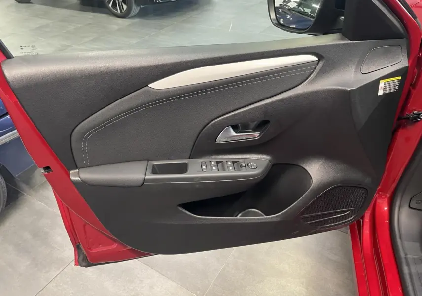 Vue intérieure de la porte avant gauche rouge d'une Opel Corsa 2026 avec commandes électriques et garniture noire.