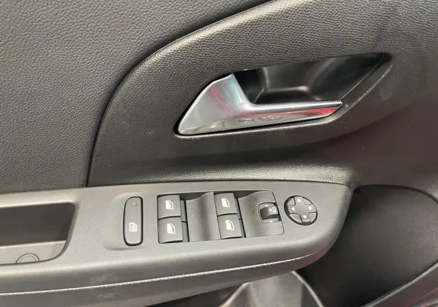 Gros plan sur la commande des vitres et rétroviseurs côté conducteur d'une Opel Corsa rouge, intérieur noir.