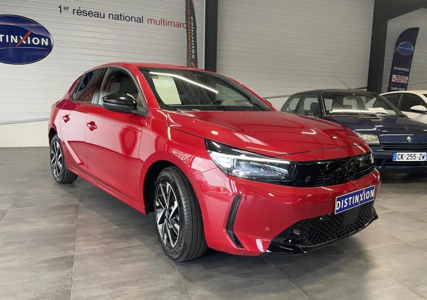 Opel Corsa rouge vue 3/4 avant droit, avec calandre noire et jantes alliage diamantées en showroom.
