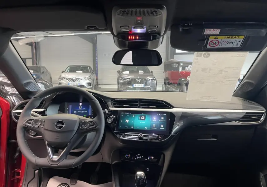 Vue intérieure avant de l’Opel Corsa rouge 2026, tableau de bord moderne avec écran tactile 10 pouces et volant multifonction.