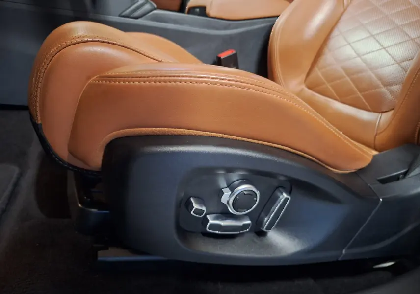 Gros plan sur le réglage électrique du siège avant en cuir marron du Jaguar E-PACE blanc, version R-DYNAMIC HSE.