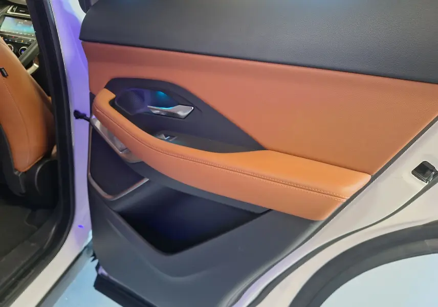 Vue intérieure de la porte arrière droite d’un Jaguar E-PACE blanc avec garniture cuir marron et détails noirs.