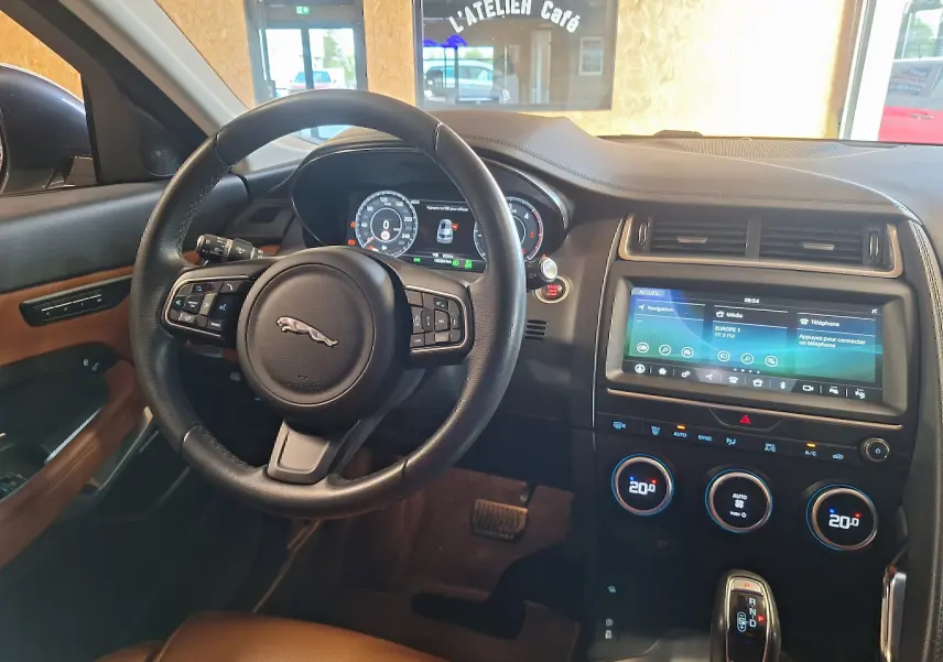 Vue intérieure avant du Jaguar E-PACE 2019, volant cuir noir et tableau de bord avec écran tactile couleur.