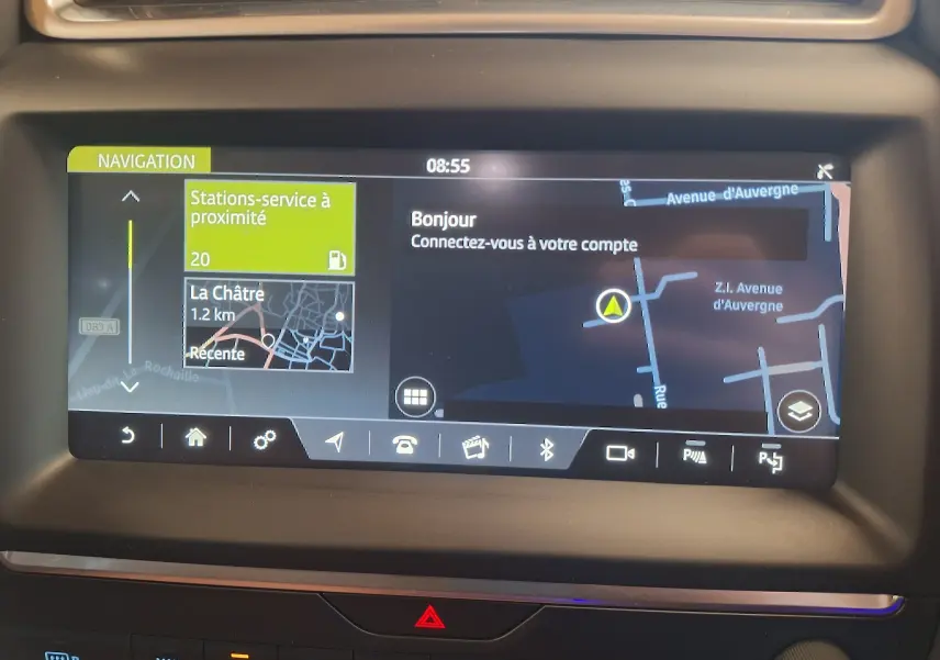 Écran tactile de navigation du Jaguar E-PACE blanc, affichant une carte avec stations-service à proximité.