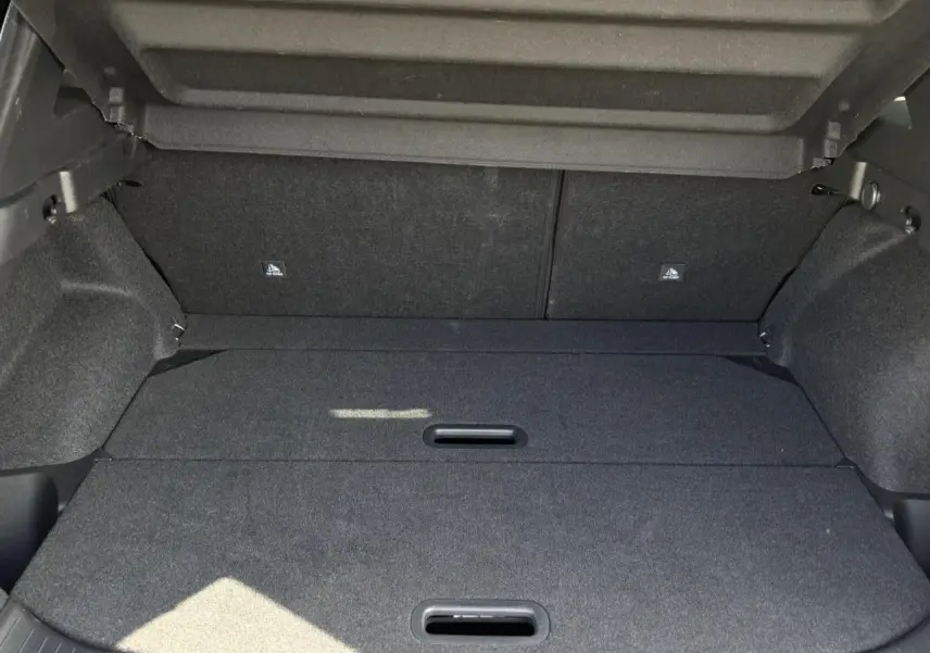 Coffre modulable ouvert du Nissan Qashqai III gris Ceramic, montrant le plancher de coffre plat et les poignées intégrées.