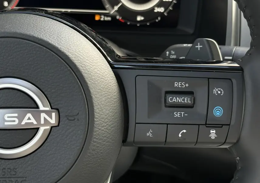 Gros plan sur les commandes à droite du volant cuir du Nissan Qashqai 2025, avec régulateur de vitesse et assistance active.