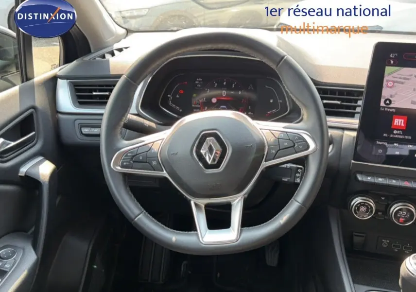 Vue intérieure centrée sur le volant du Renault Captur 1.3 TCe bleu marine fumé, avec tableau de bord numérique et écran tactile.