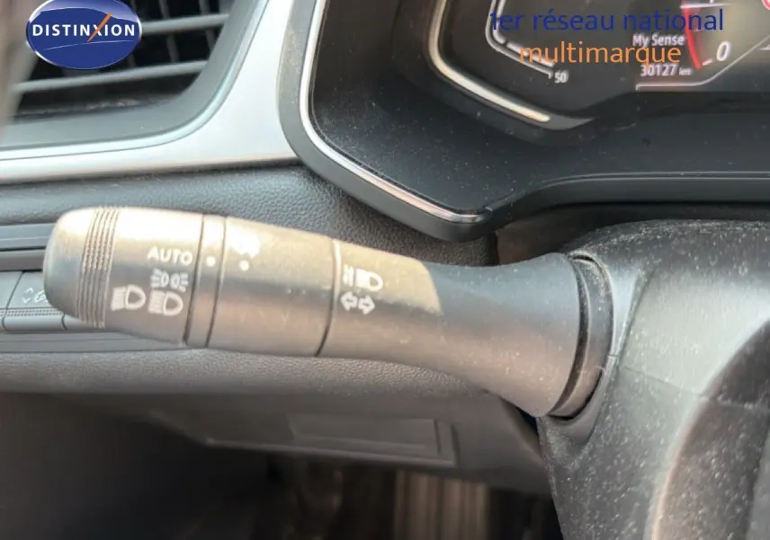 Gros plan sur la manette de clignotant à gauche du volant dans l'habitacle du Renault Captur bleu marine fumé.