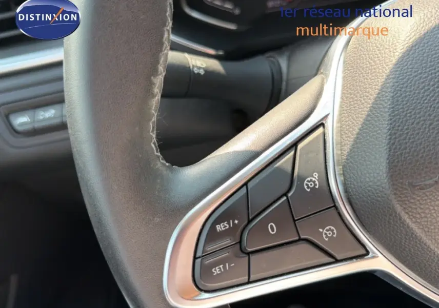 Gros plan sur les commandes au volant du Renault Captur bleu marine fumé, mettant en valeur les boutons de régulateur de vitesse.