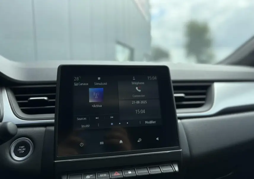 Vue intérieure centrée sur l'écran tactile Easy Link 7" du Renault Captur blanc nacré 2022 avec bouton start/stop.