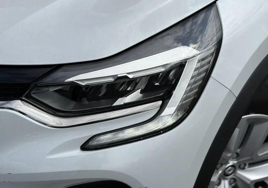 Gros plan sur le phare avant droit du Renault Captur blanc nacré 2022 avec jante alliage visible.