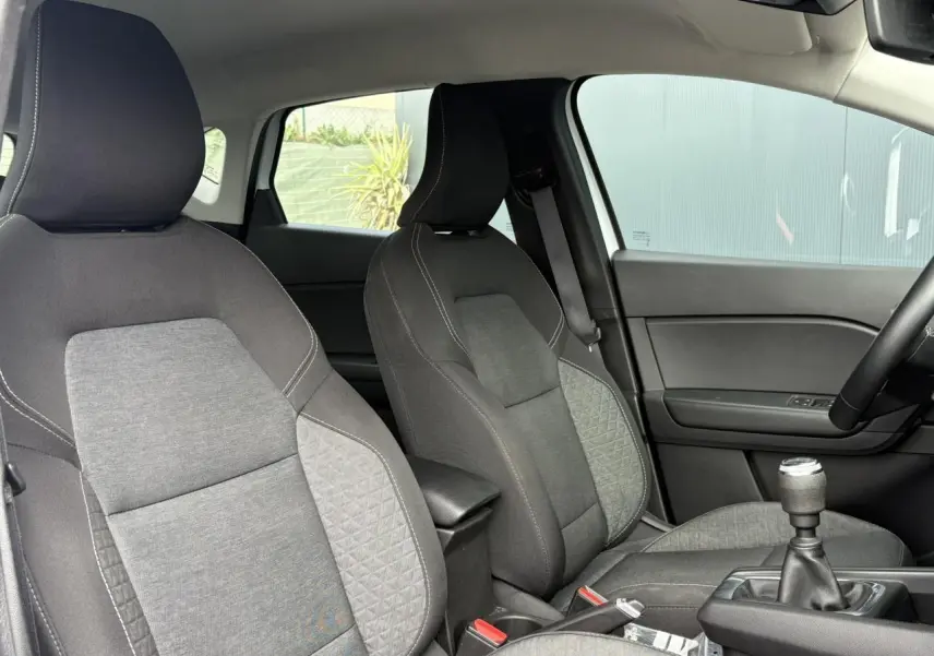 Vue intérieure sur les sièges avant gris et la console centrale avec levier de vitesses manuelle du Renault Captur blanc nacré 2022.