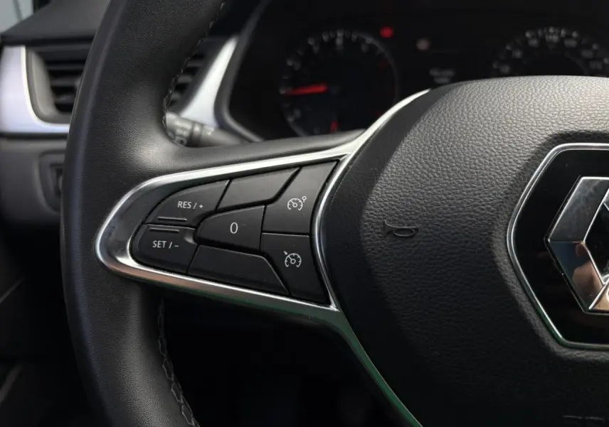 Gros plan sur le volant noir du Renault Captur TCE 90 Business 2022, avec commandes de régulateur de vitesse.