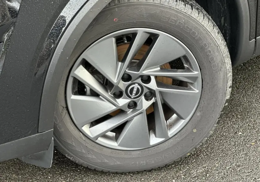 Gros plan sur la jante alliage 17 pouces grise du Nissan Qashqai noir nacré, côté avant gauche, avec logo Nissan visible.