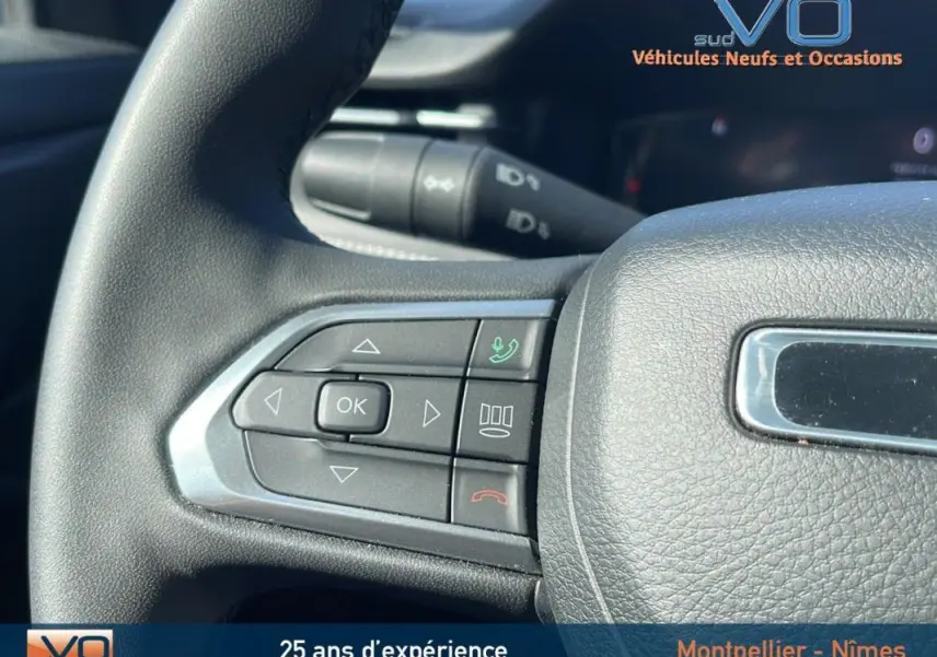 Gros plan sur les commandes du volant en cuir noir du Jeep Compass 2023 Limited, avec boutons multifonctions visibles.