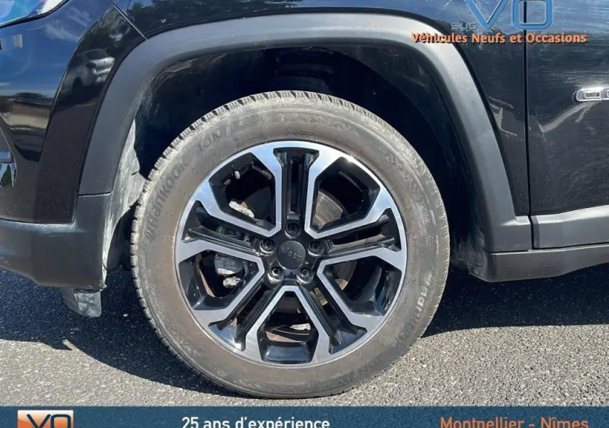 Gros plan sur la roue avant gauche noire du Jeep Compass 2023 avec jante alliage 18 pouces et logo Jeep au centre.