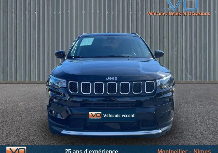 Vue frontale d'un Jeep Compass noir 2023 avec calandre distinctive et phares LED allumés sur fond neutre.