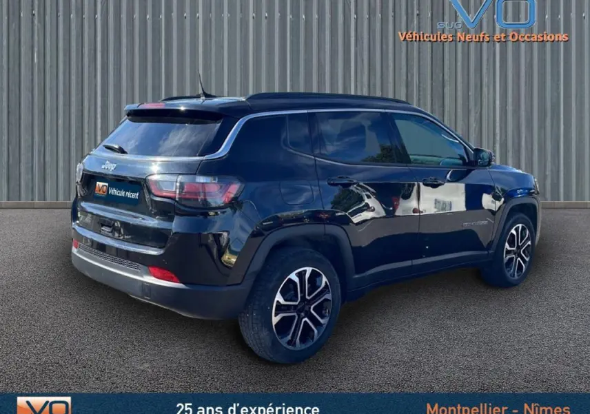 Jeep Compass noir en 3/4 arrière droit, avec barres de toit et jantes 18 pouces visibles sur fond urbain.