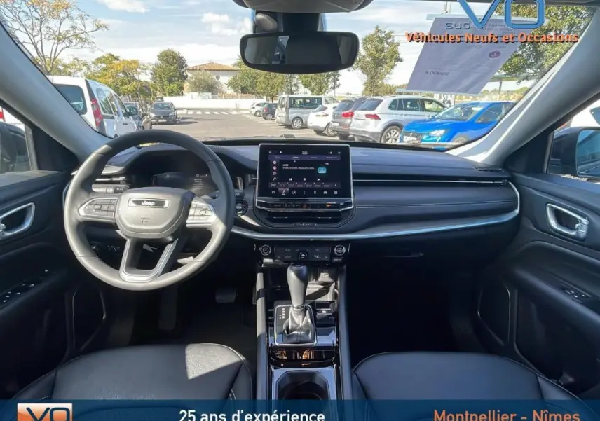Intérieur du Jeep Compass 2023 noir vu de face, avec écran tactile central et volant multifonction en cuir.