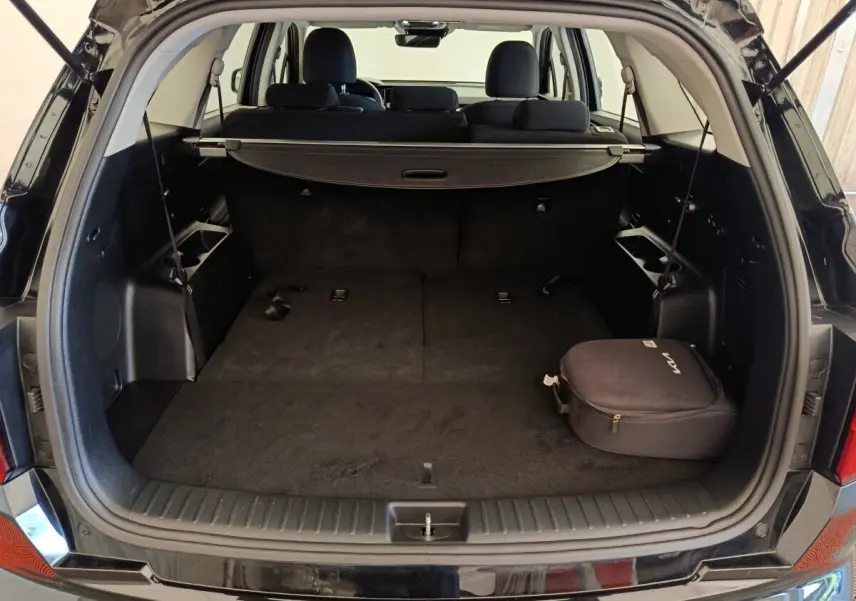 Coffre ouvert du Kia Sorento noir 2023 vu de l'arrière, avec plancher plat et cache-bagages déployé.