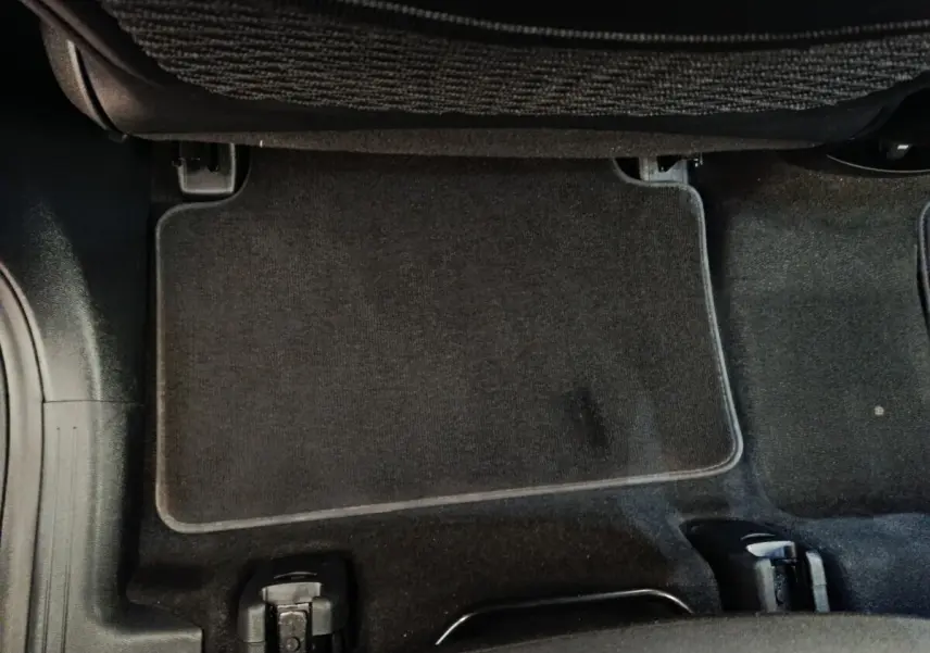 Vue rapprochée du tapis de sol noir sous le siège arrière d'un KIA Sorento 2023 hybride rechargeable.