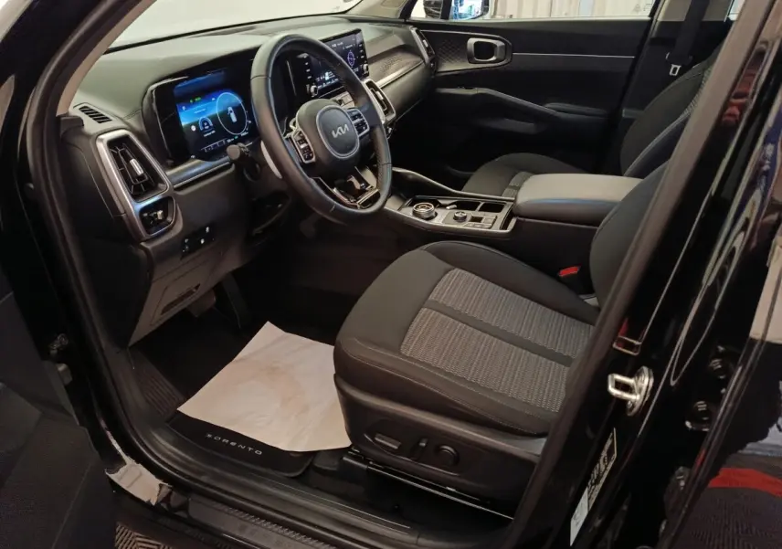 Vue intérieure côté conducteur du Kia Sorento noir 2023, avec tableau de bord digital et sièges tissu gris.