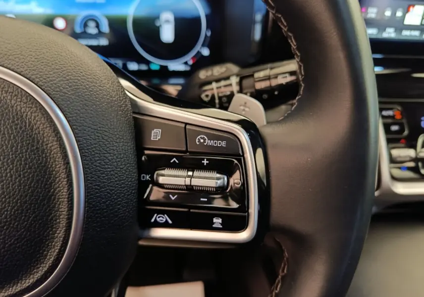 Gros plan sur les commandes multifonctions à droite du volant cuir noir du Kia Sorento hybride 2023.