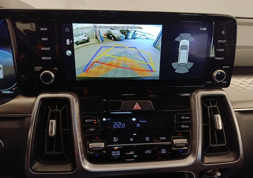 Vue rapprochée de l’écran tactile central du tableau de bord du Kia Sorento noir, affichant la caméra de recul et les commandes climatisation.