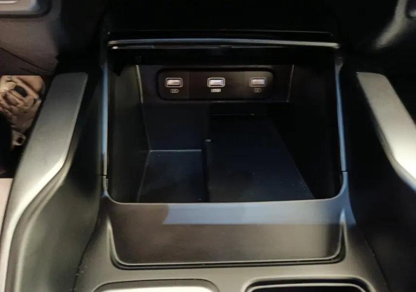 Gros plan sur la console centrale noire du Kia Sorento 2023, montrant trois ports USB alignés.