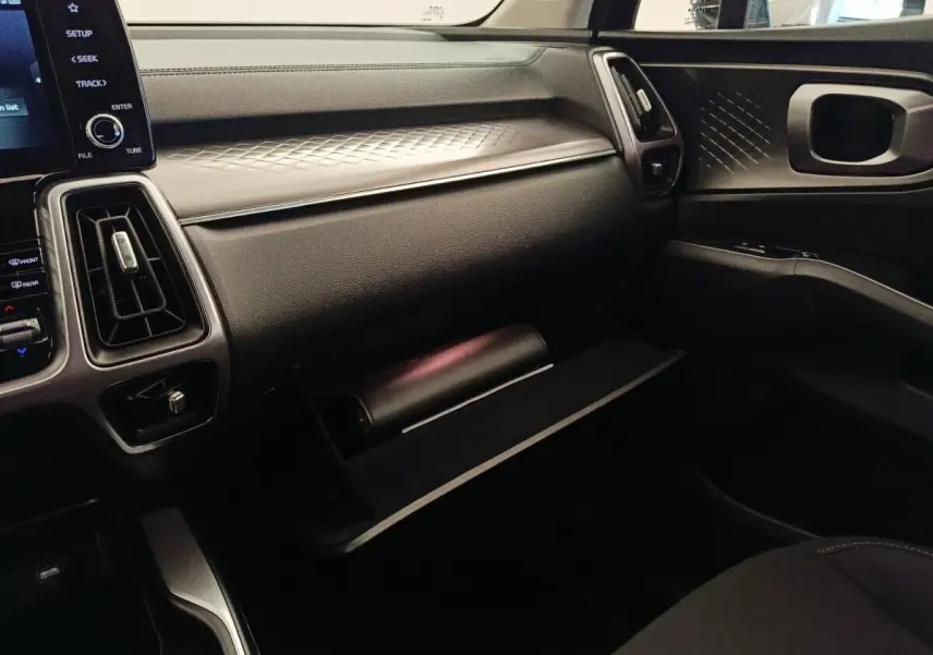 Intérieur KIA Sorento 2023 vue côté passager, tableau de bord noir avec boîte à gants ouverte et détails texturés.