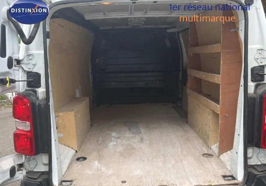 Vue arrière ouverte du Citroën Jumpy XL blanc de 2017, montrant l’espace de chargement avec étagères en bois.