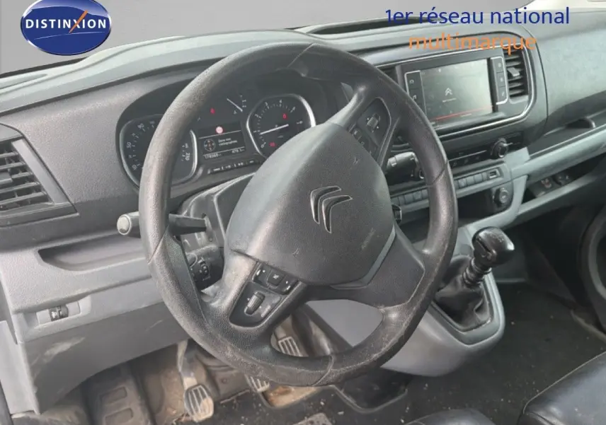Vue intérieure du poste de conduite du Citroën Jumpy blanc, volant multifonction et levier de vitesses manuel visibles.