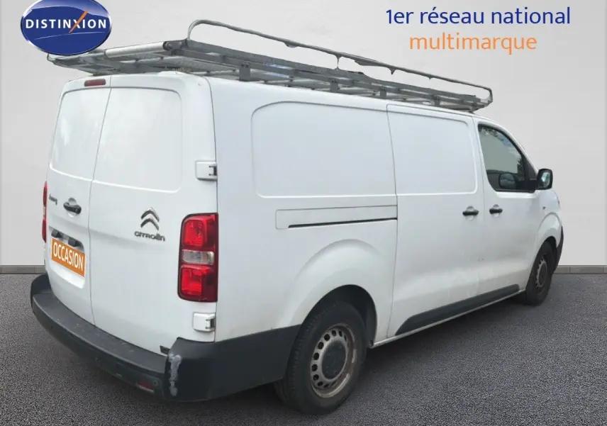 Vue 3/4 arrière droite d’un Citroën Jumpy blanc avec galerie de toit et pare-chocs arrière noir.
