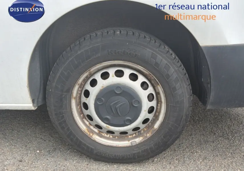 Gros plan sur la roue avant gauche d’un Citroën Jumpy blanc de 2017, jante acier avec traces de rouille.