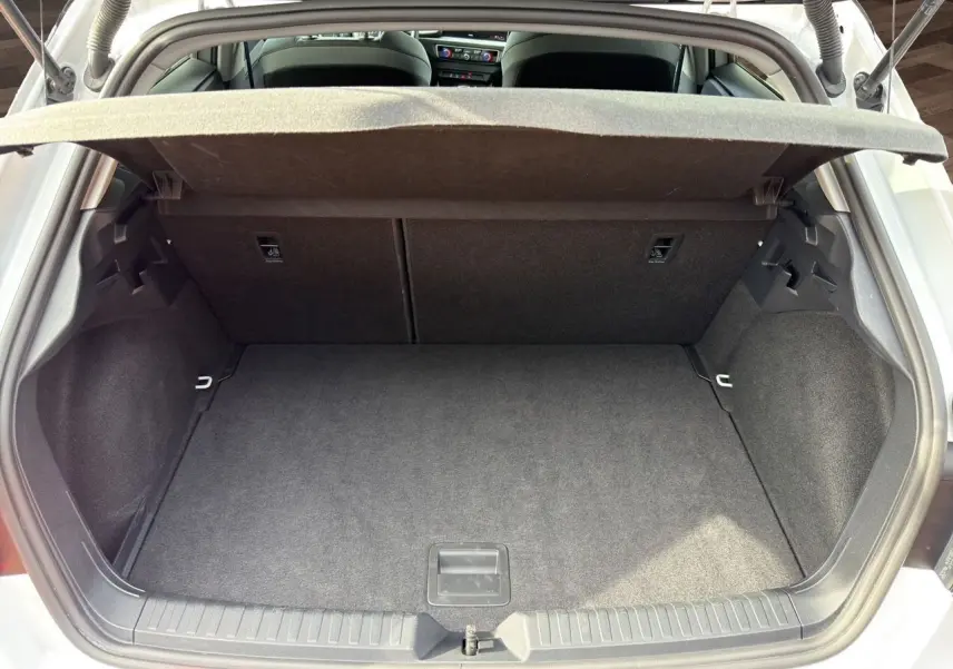 Coffre ouvert vu de l'arrière d'une Audi A1 Sportback blanche, montrant un espace de chargement propre et vide.