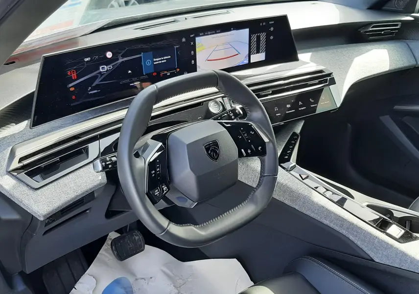 Vue intérieure du tableau de bord du Peugeot 5008 Hybrid 2025, avec volant compact et écran panoramique i-Cockpit.