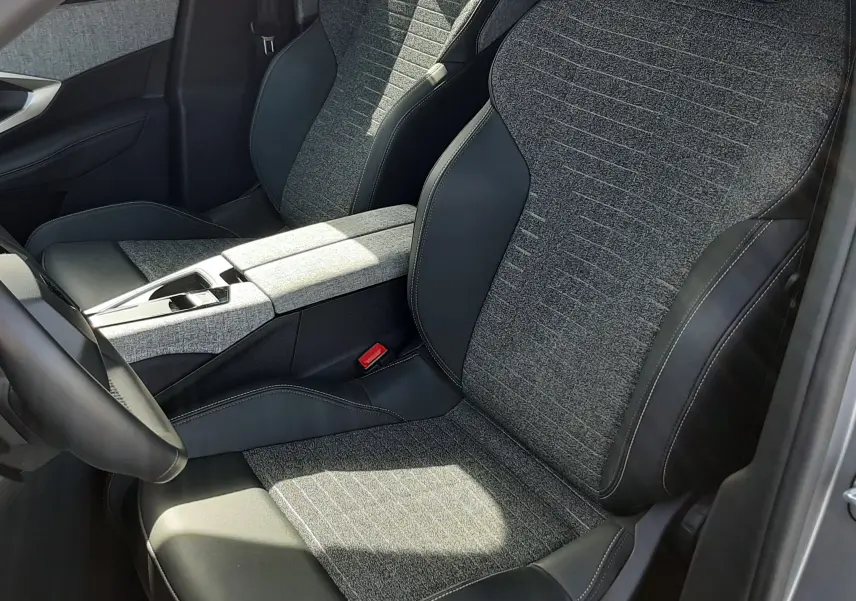 Vue intérieure rapprochée des sièges avant gris tissu et cuir noir du Peugeot 5008 Hybrid 2025, avec console centrale assortie.