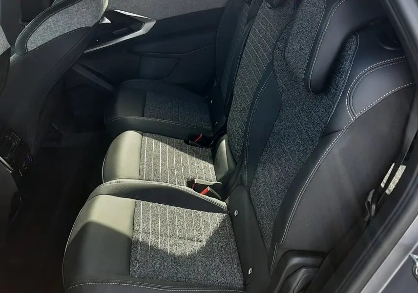 Vue latérale droite de la banquette arrière du Peugeot 5008 Hybrid 2025 avec sièges tissu et cuir gris noir.