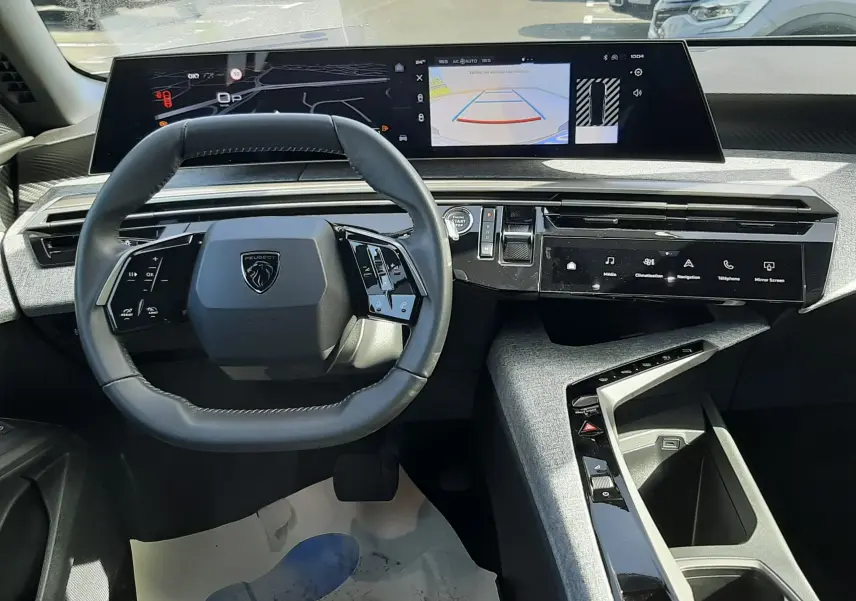 Vue intérieure du tableau de bord du Peugeot 5008 Hybrid gris, avec volant compact et écran tactile panoramique I-Cockpit.