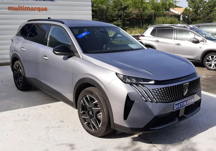Peugeot 5008 Hybrid gris Artense métal en 3/4 avant droit, avec calandre distinctive et jantes noires.