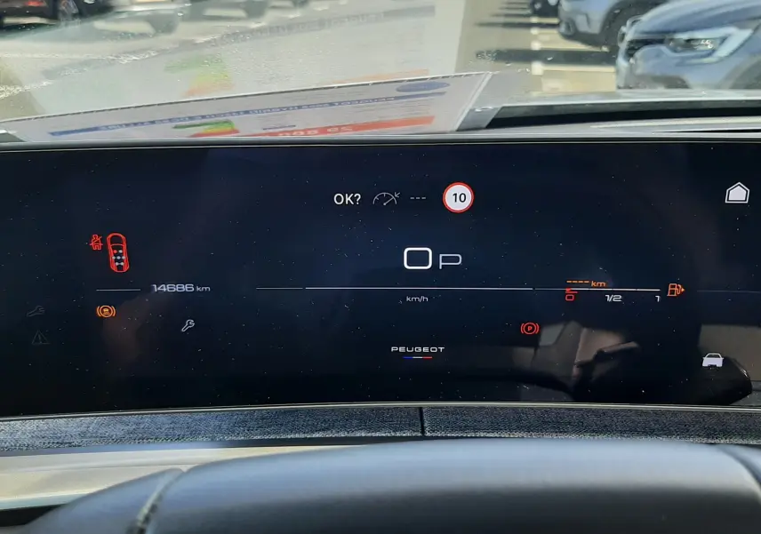 Vue rapprochée du tableau de bord numérique du Peugeot 5008 Hybrid gris, affichant la vitesse à 0 km/h et divers indicateurs.