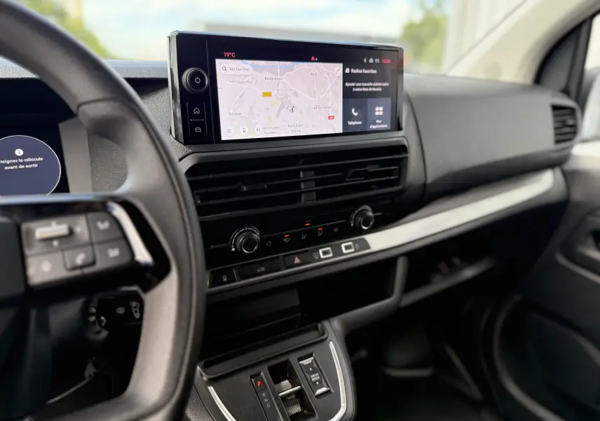 Intérieur du FIAT Scudo Fourgon blanc, vue du tableau de bord avec écran tactile affichant la navigation et commandes modernes.