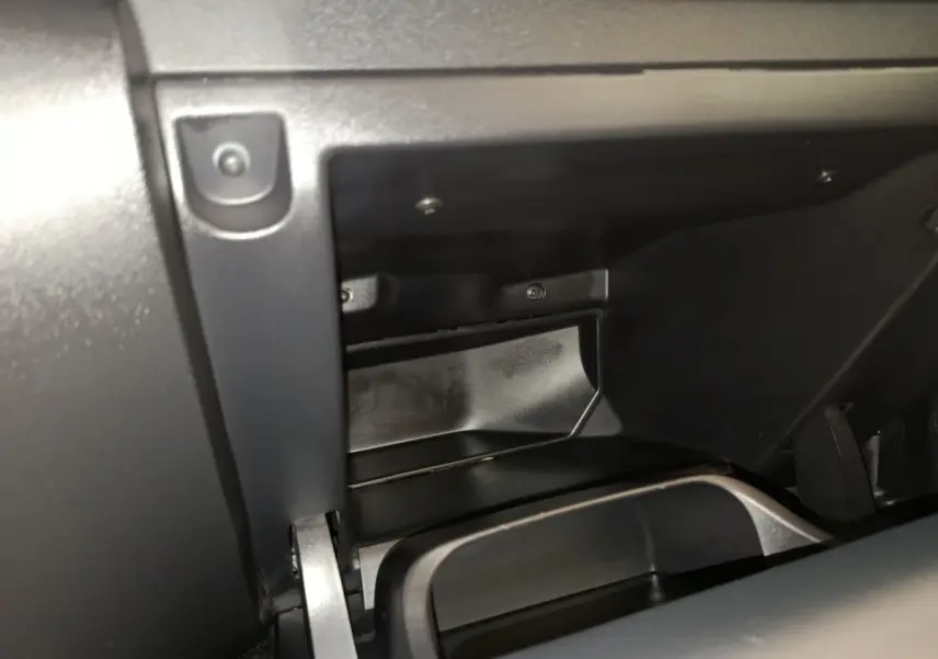 Vue rapprochée de la boîte à gants ouverte du Citroën C3 2024 gris foncé, montrant l'intérieur en plastique noir.