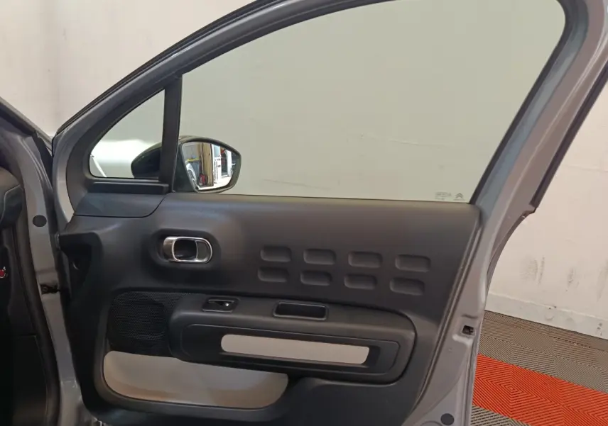 Vue intérieure du côté gauche de la porte arrière gris foncé de la Citroën C3 avec poignée chromée et inserts noirs.