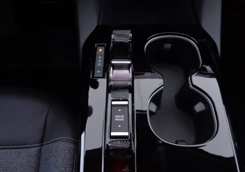 Gros plan sur la console centrale noire brillante de la Citroën C5 X 2023, avec sélecteur de boîte auto et porte-gobelets.