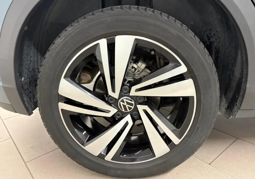 Gros plan sur la jante alliage bicolore du Volkswagen T-Roc 2024 bleu pétrole, version R-Line avec logo VW central.